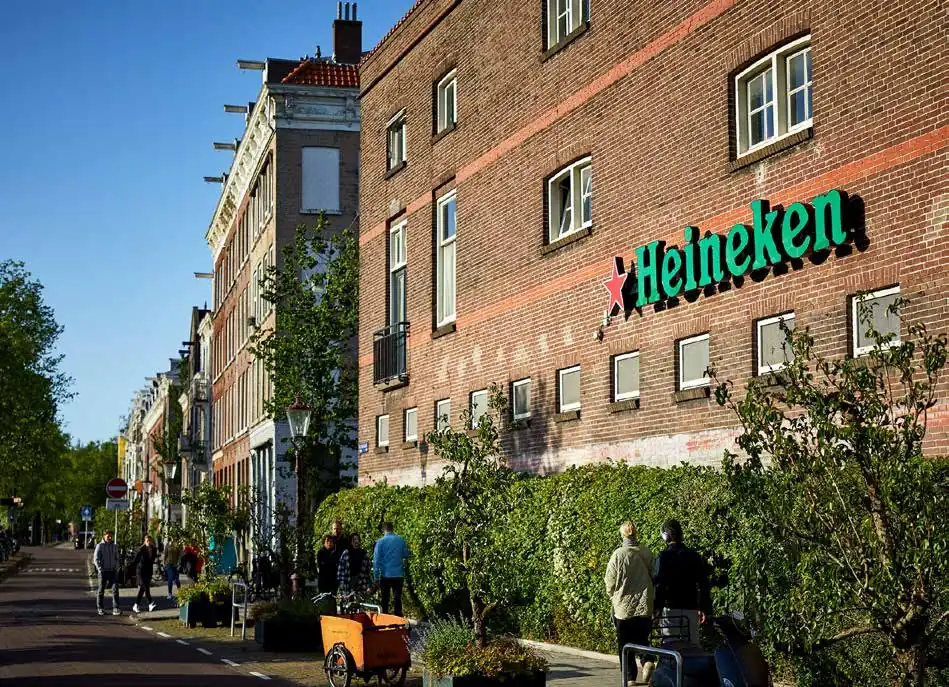 Straatbeeld van de Ruysdaelkade in Amsterdam met het Heineken-logo op een bakstenen gevel.