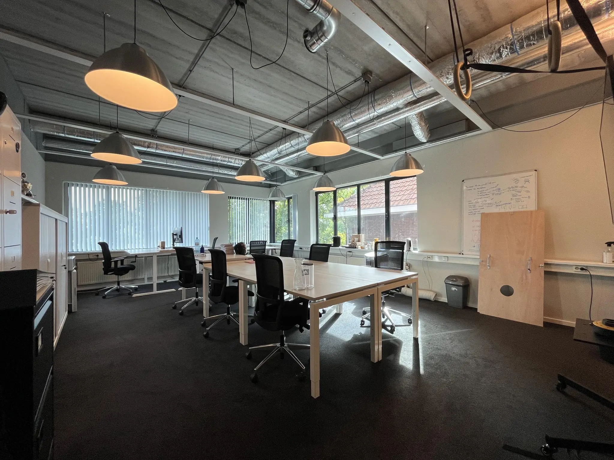 Moderne kantoorruimte aan de Kanaalweg met bureaus, bureaustoelen, hanglampen en een whiteboard.