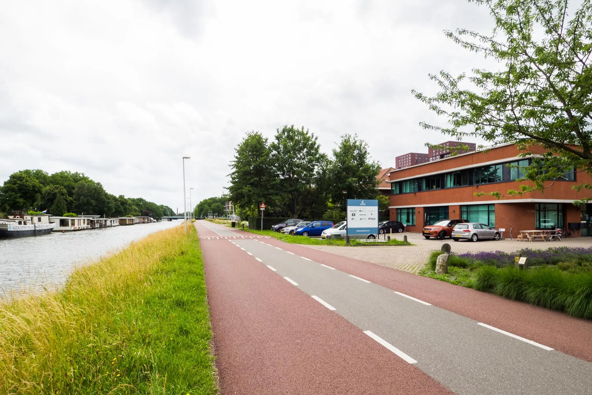 Fiets- en wandelpad langs het kanaal met aan de rechterkant een rood bakstenen kantoorgebouw aan de Kanaalweg.