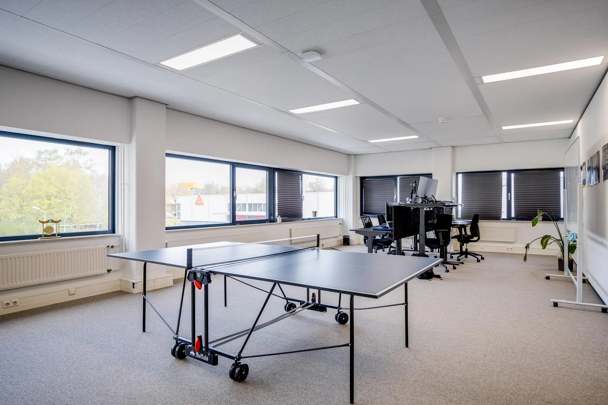 Modern kantoor aan de Zonnebaan met werkplekken, grote ramen en een tafeltennistafel op de voorgrond.