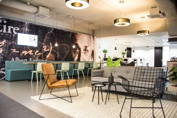 Moderne lounge- en werkruimte met zitgedeelte, wanddecoratie van Albert Einstein en strakke industriële inrichting aan de Meidoornkade.