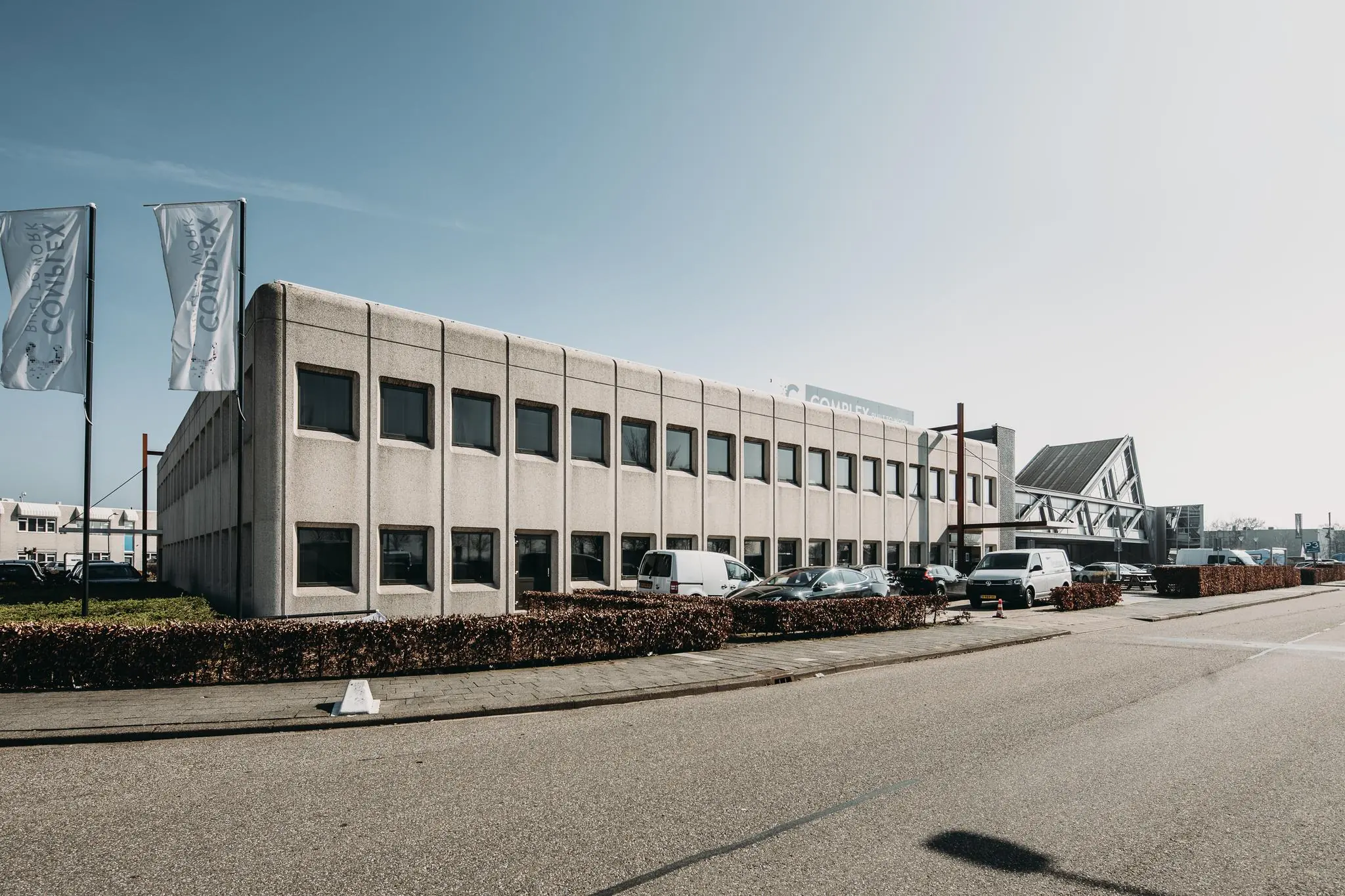 Kantoorpand aan de Meidoornkade met parkeerplaatsen en vlaggen van bedrijvencentrum Complex.