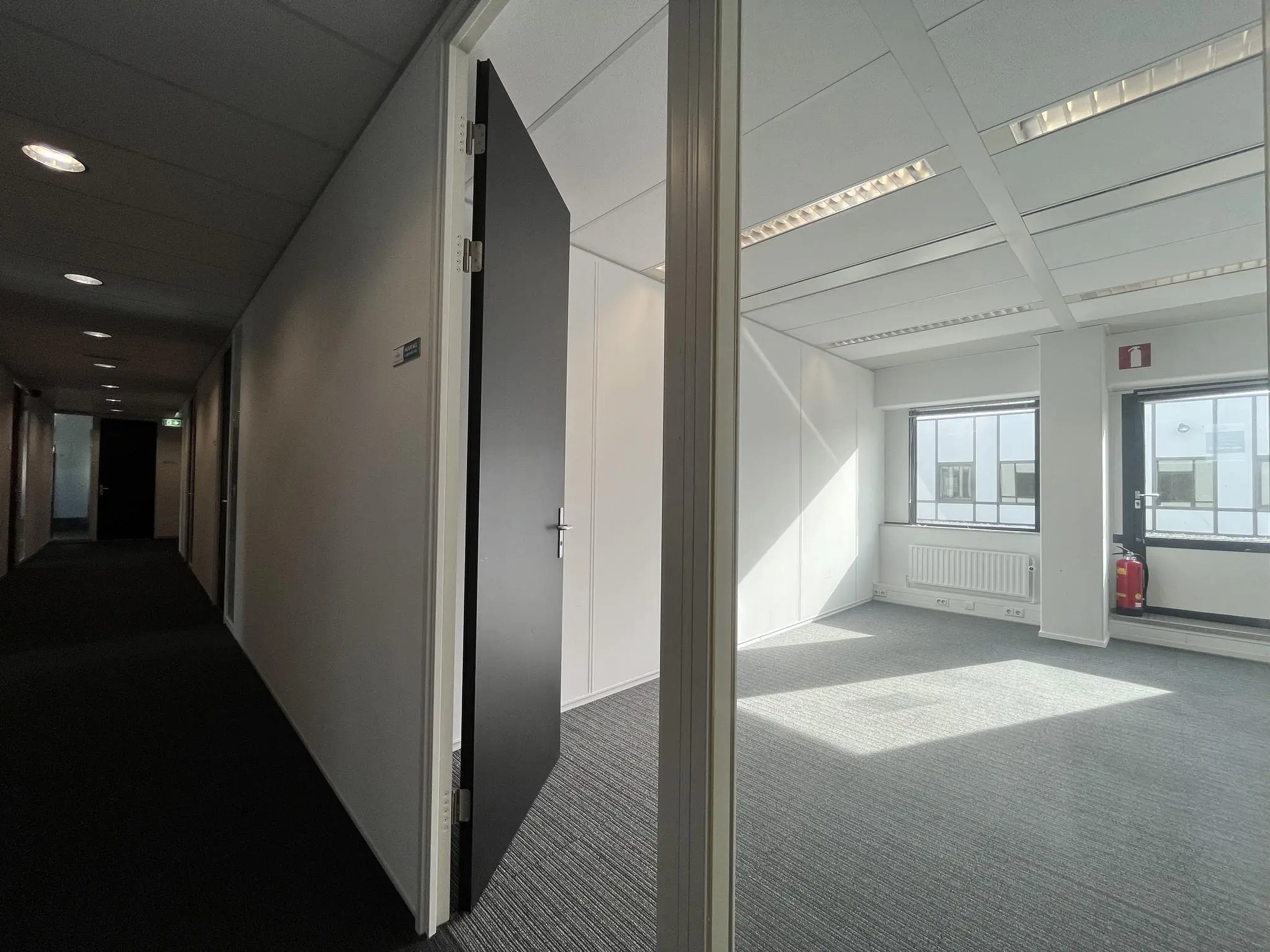 Lichte, lege kantoorruimte aan de Meidoornkade met open deur grenzend aan een donkere gang.