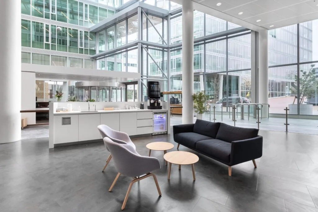Moderne en lichte ontvangstruimte in Kennedy Tower aan het Kennedyplein 200 in Eindhoven met zithoek, koffiecorner en grote glazen gevels.