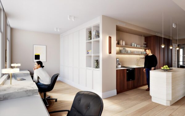 Moderne woonruimte aan het Rokin met een werkplek bij het raam en een open keuken waar een man staat.