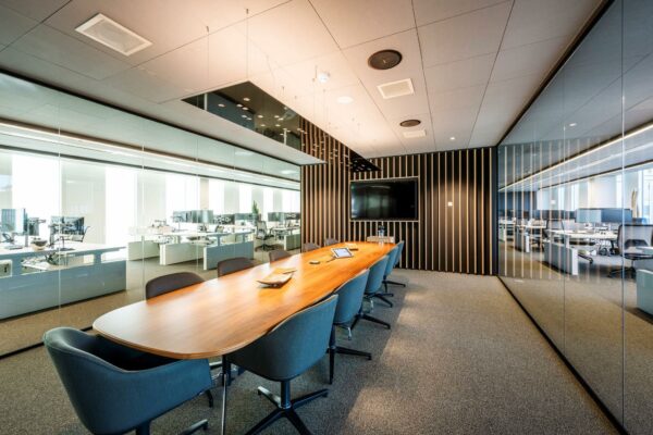 Vergaderruimte in kantoorgebouw Hoekenrode met houten tafel, moderne stoelen en glazen wanden met zicht op werkplekken.