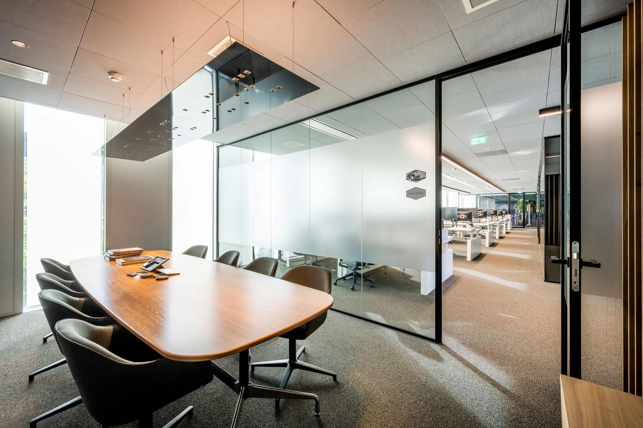 Moderne vergaderruimte in kantoorpand Hoekenrode met glazen wanden en uitzicht op een open kantoorruimte.