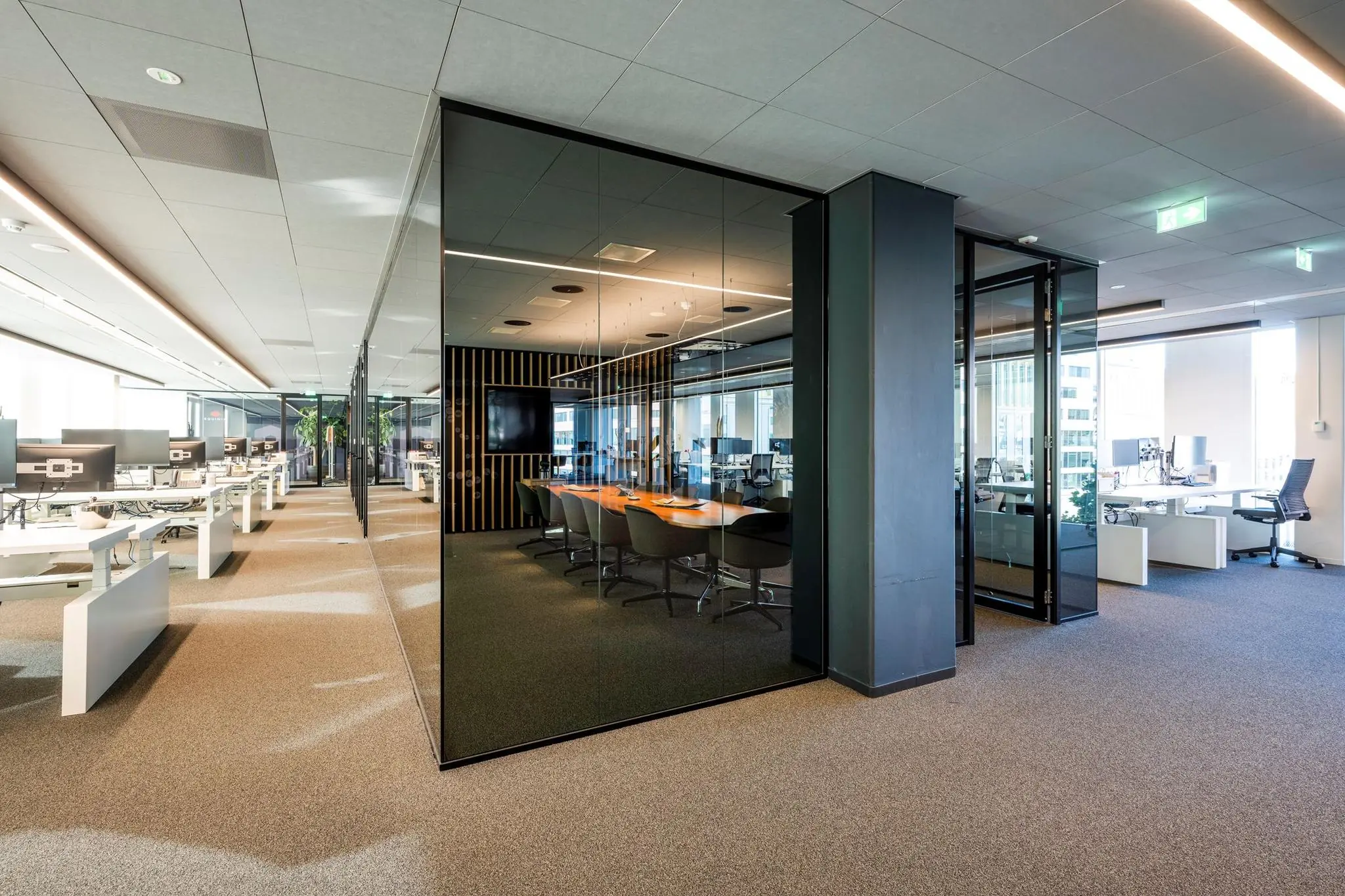 Moderne open kantoorruimte in Hoekenrode met glazen vergaderruimte en werkplekken met computers.