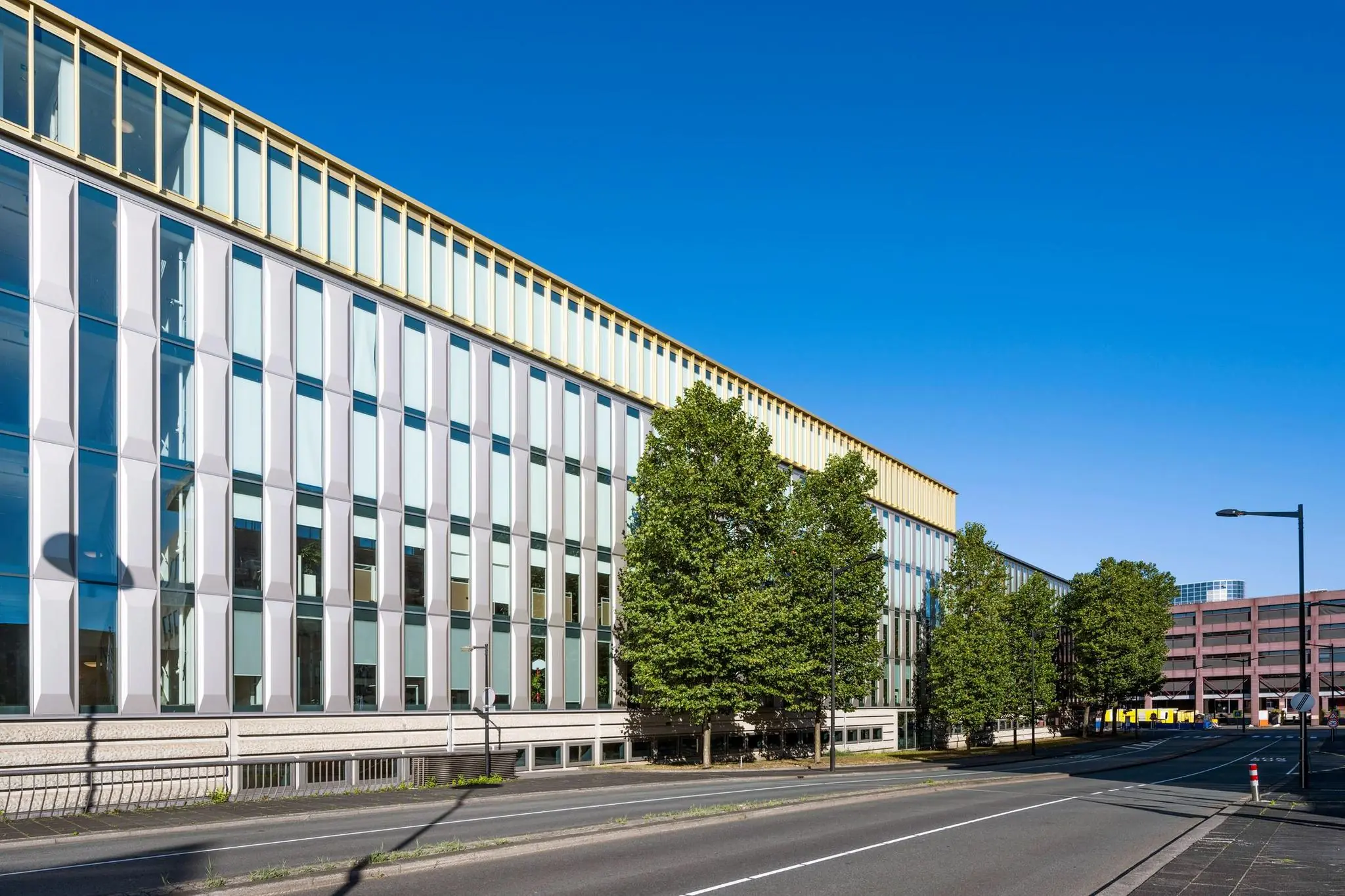 Modern kantoorgebouw Hoekenrode in Amsterdam-Zuidoost met glasgevel en bomen langs de weg.