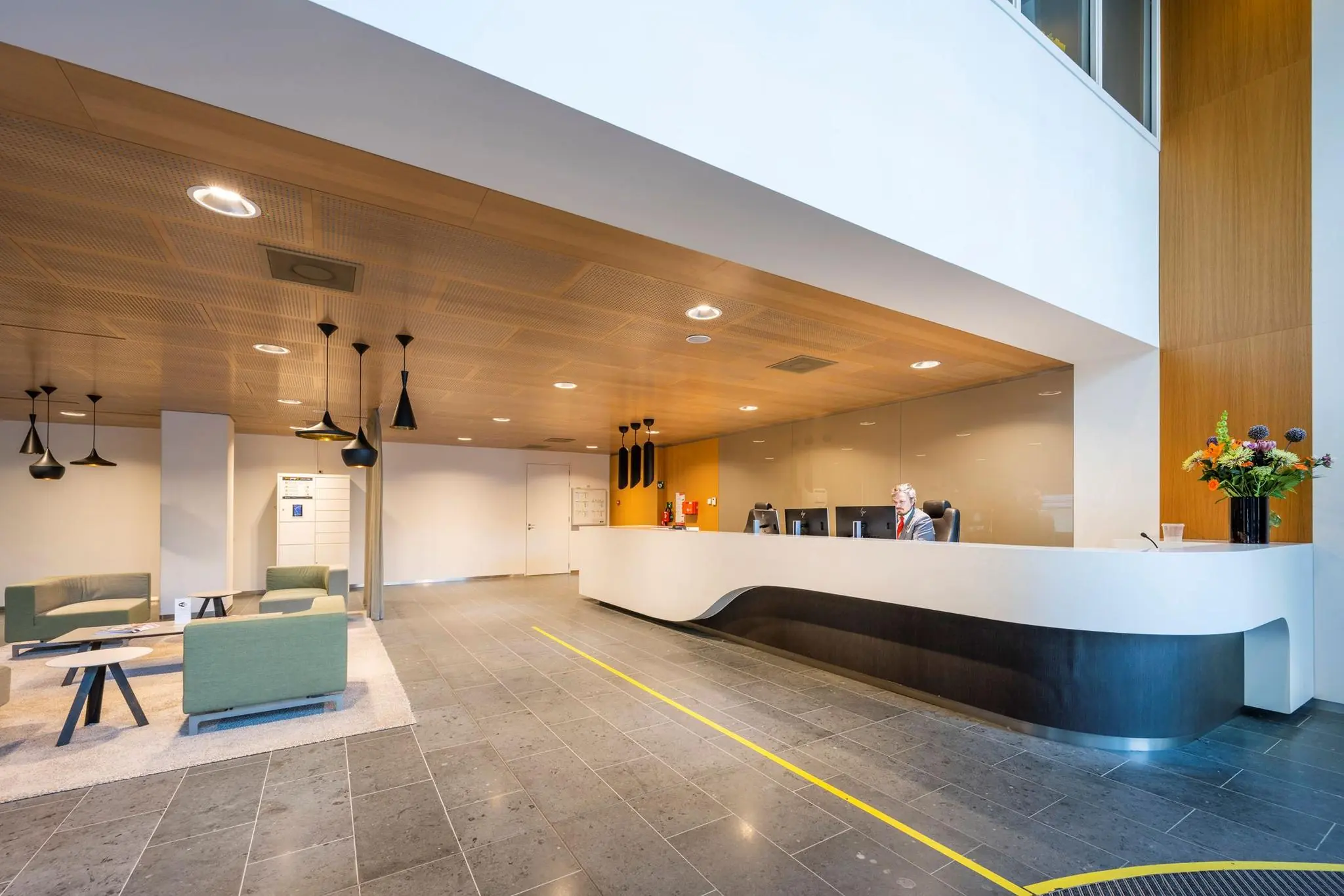 Moderne en lichte receptieruimte van kantoorgebouw Hoekenrode met zitgedeelte en baliemedewerker.