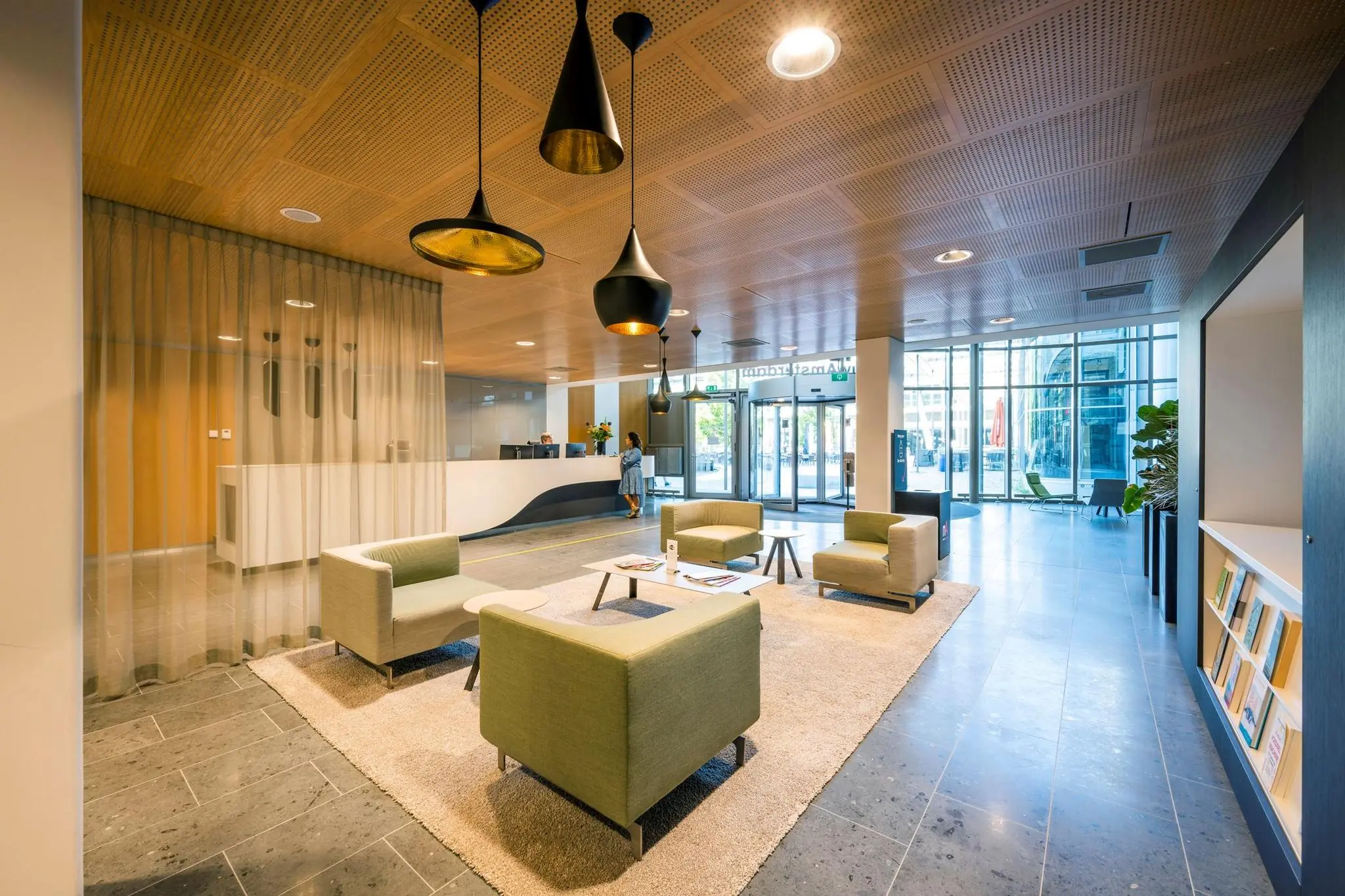 Moderne en lichte ontvangsthal van het kantoorgebouw Hoekenrode met zithoek, receptie en glazen entree.