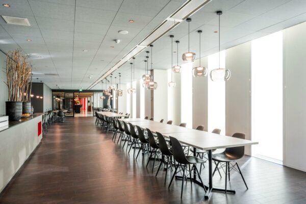 Moderne en strak ingerichte vergaderruimte in gebouw Hoekenrode met lange tafel, zwarte stoelen en hanglampen.