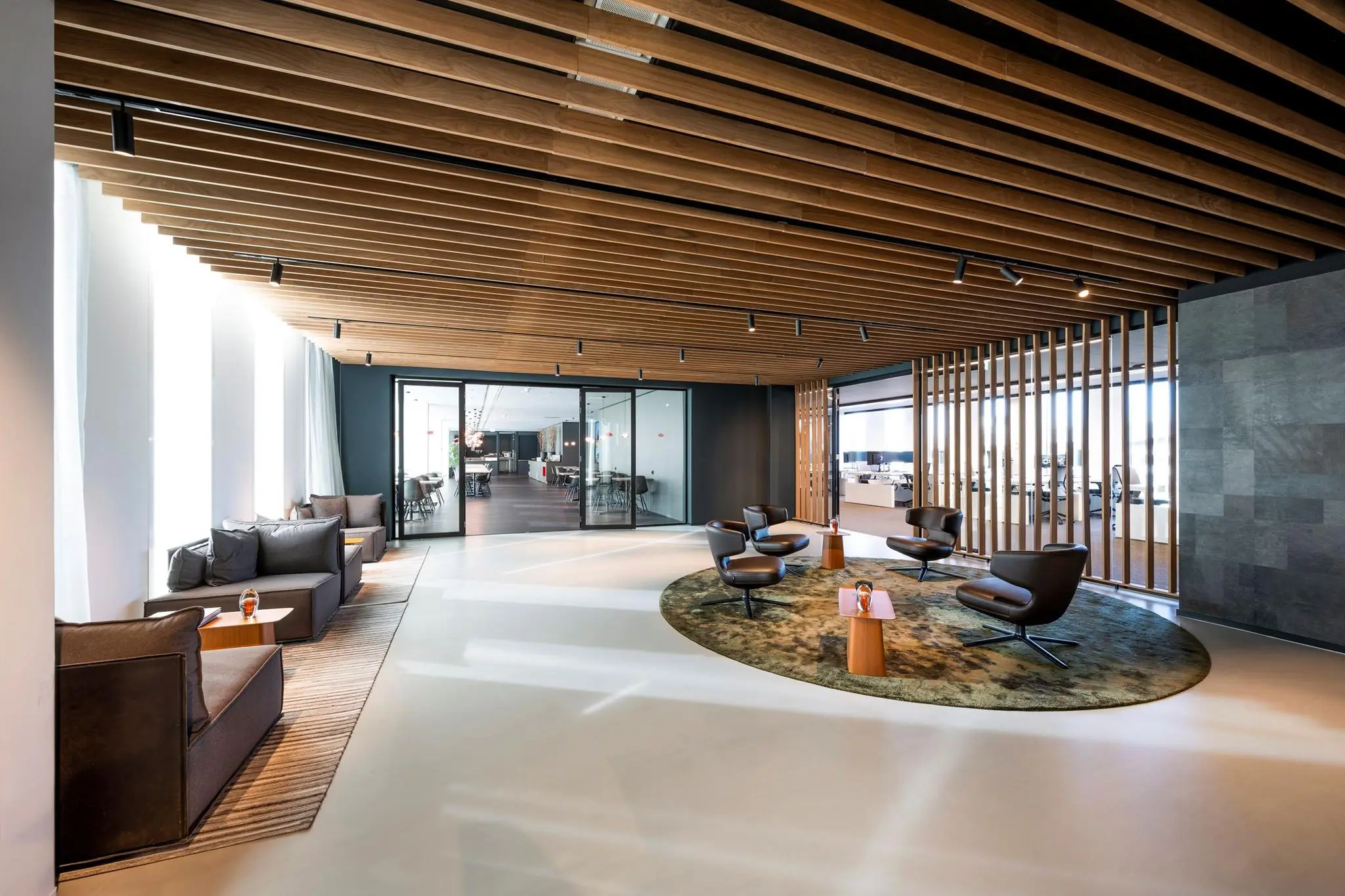 Moderne wachtruimte in kantoorgebouw Hoekenrode met designmeubilair en houten plafondaccenten.