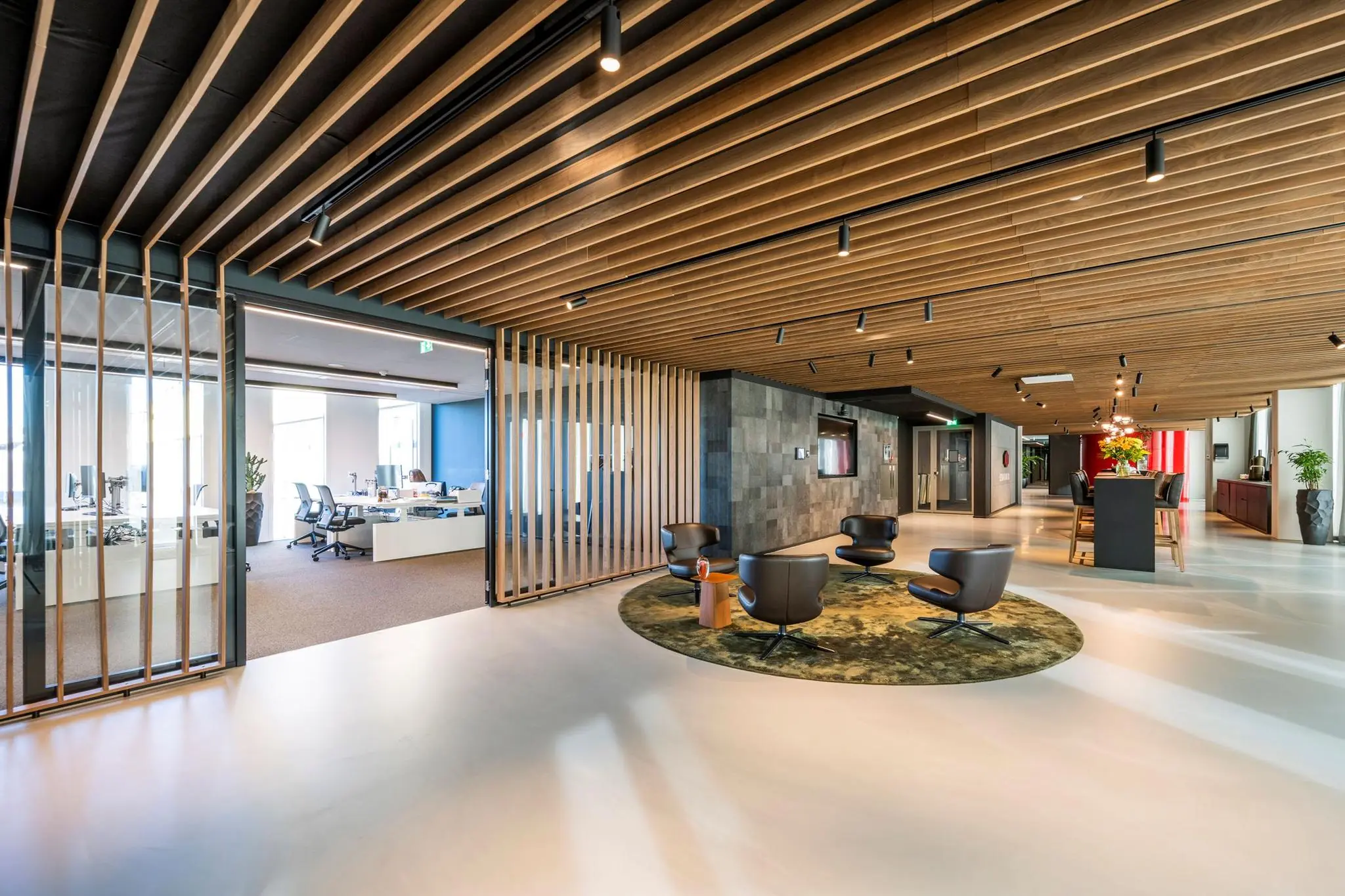 Moderne kantoorruimte in Hoekenrode met open werkplekken, zithoek en houten plafondaccenten.