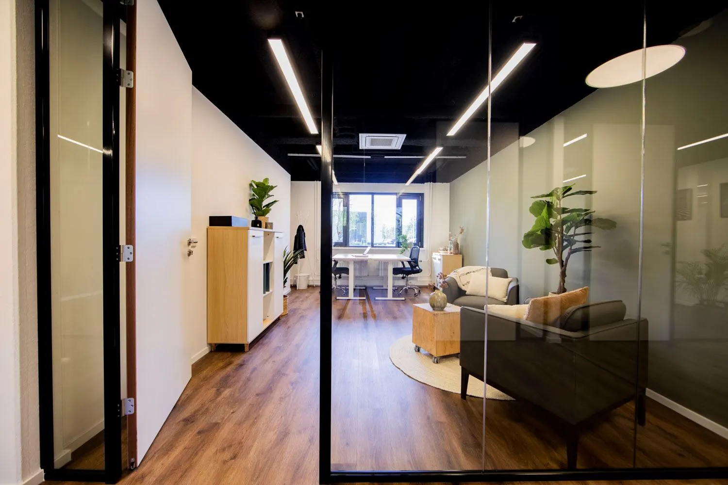 Modern ingericht kantoor aan de Rietbaan met glazen wanden, houten vloer en comfortabele zitruimte.