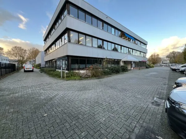 Kantoorpand aan de Industrieweg met parkeergelegenheid en omliggende bedrijfswagens.
