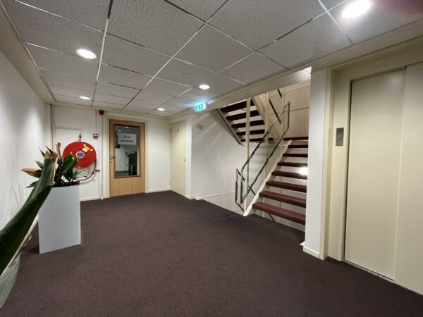 Binnenhal van een kantoorpand aan de Industrieweg met een trap, lift, brandslanghaspel en een deur naar kantoorruimte van Iivis Incase.