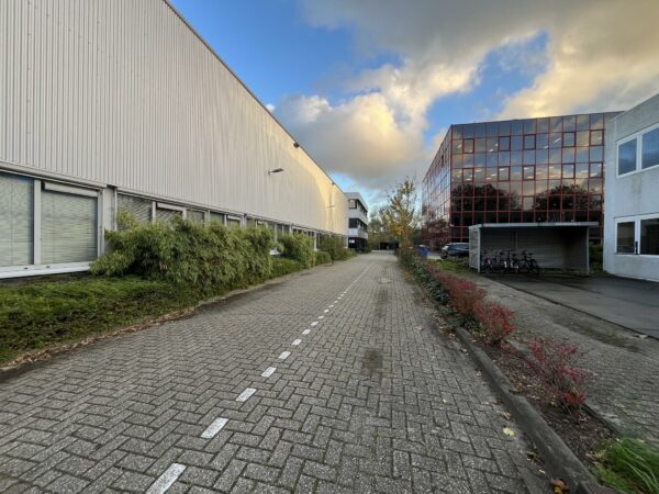 Bedrijventerrein aan de Industrieweg met kantoor- en bedrijfsgebouwen langs een betegeld pad bij zonsondergang.