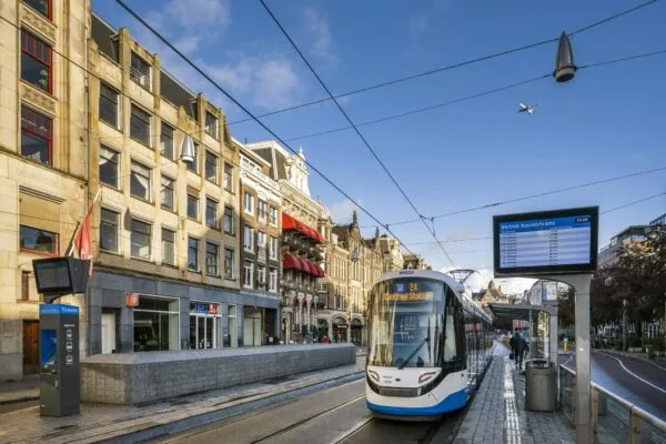 Moderne tram op lijn 24 richting Centraal Station bij de halte Rokin in Amsterdam, met historische gevels en een vertrekbord op de achtergrond.