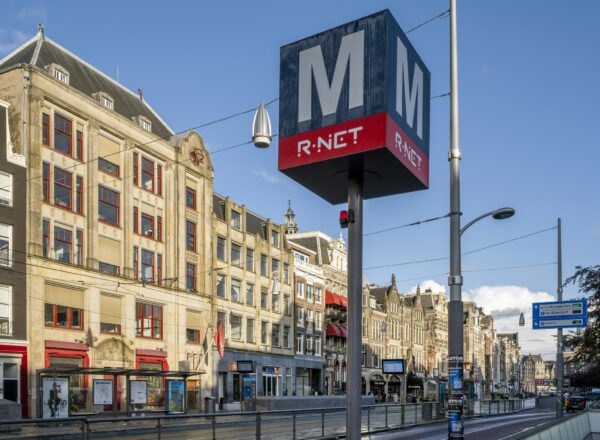 Metro-ingang van R-NET op het Rokin in Amsterdam met historische gevels op de achtergrond.