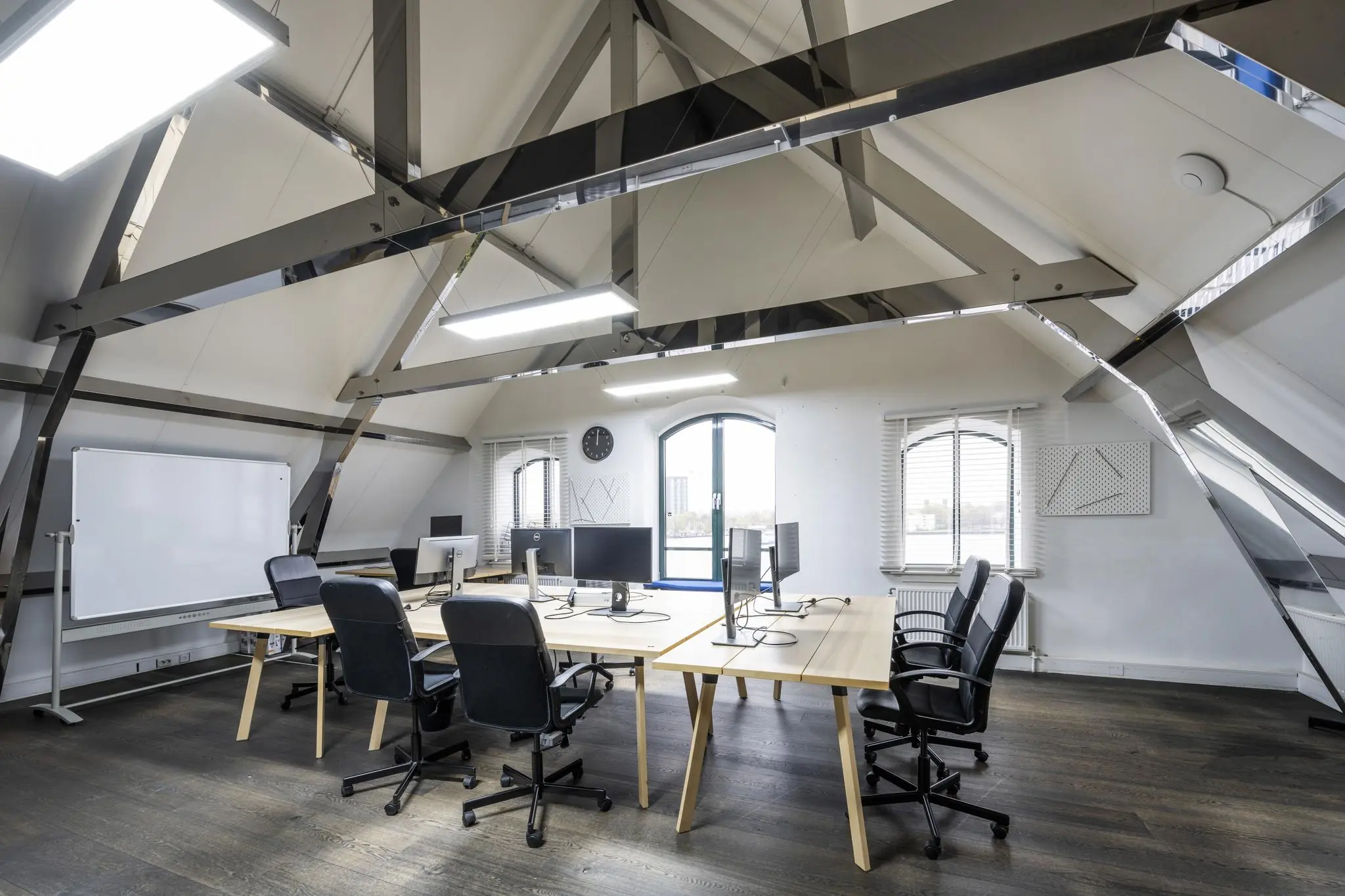 Moderne kantoorruimte aan de De Ruijterkade met houten vloeren, schuine plafonds, werkplekken en zicht op het water.