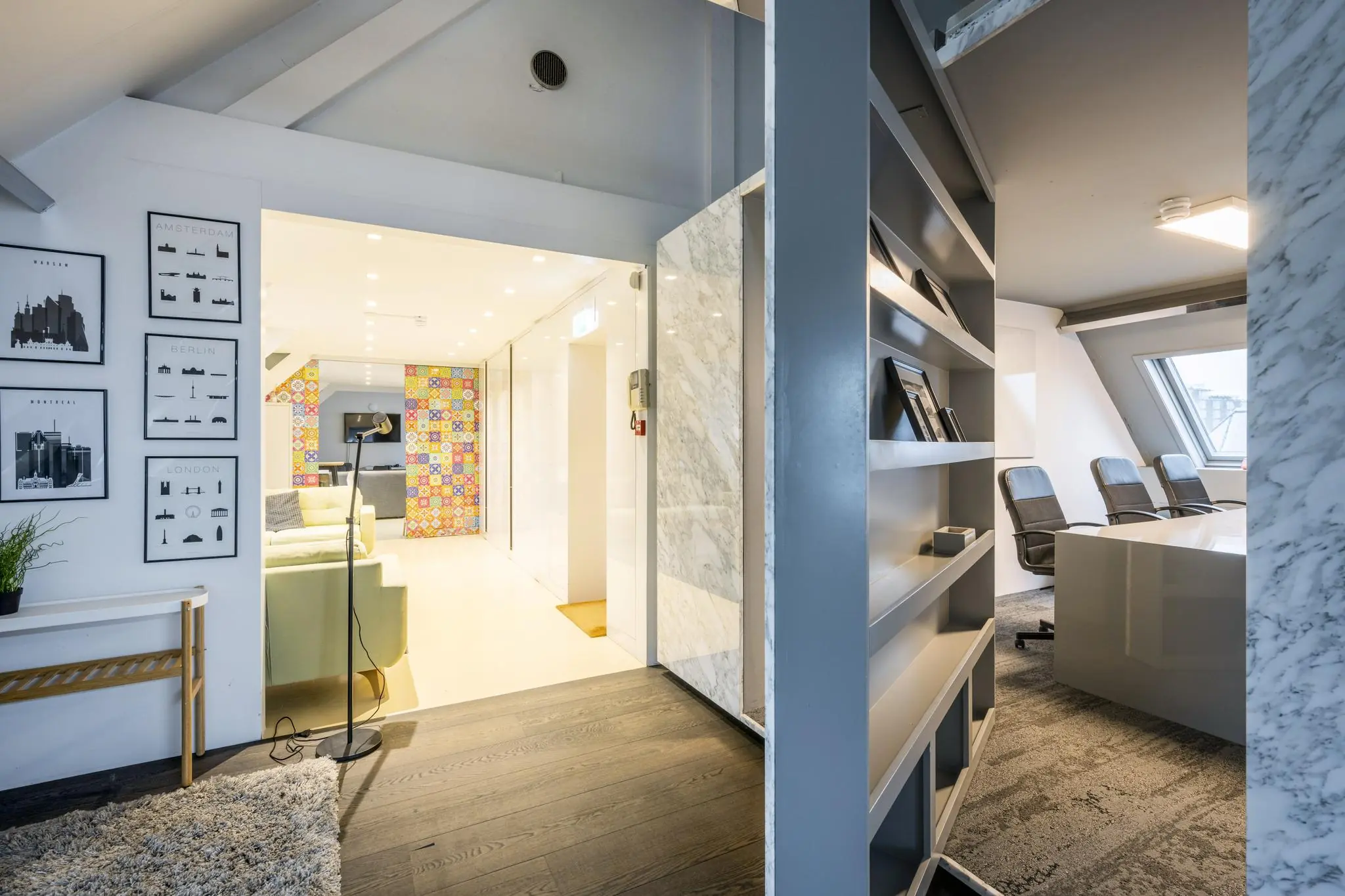 Modern interieur van een kantoorruimte aan de De Ruijterkade met vergadertafel, boekenplanken en kleurrijke wanddecoratie in de loungehoek.