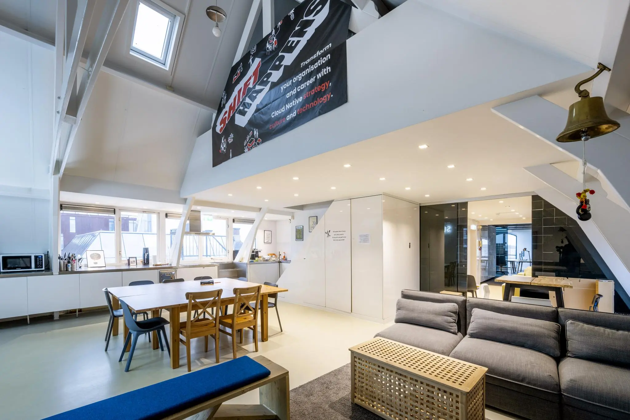 Moderne, open kantoorruimte aan de De Ruijterkade met zithoek, vergadertafel, keukenfaciliteiten en hoog plafond.