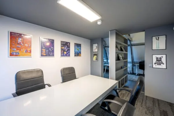 Vergaderruimte aan de De Ruijterkade met moderne inrichting, designstoelen, witte tafel en kleurrijke posters aan de muur.