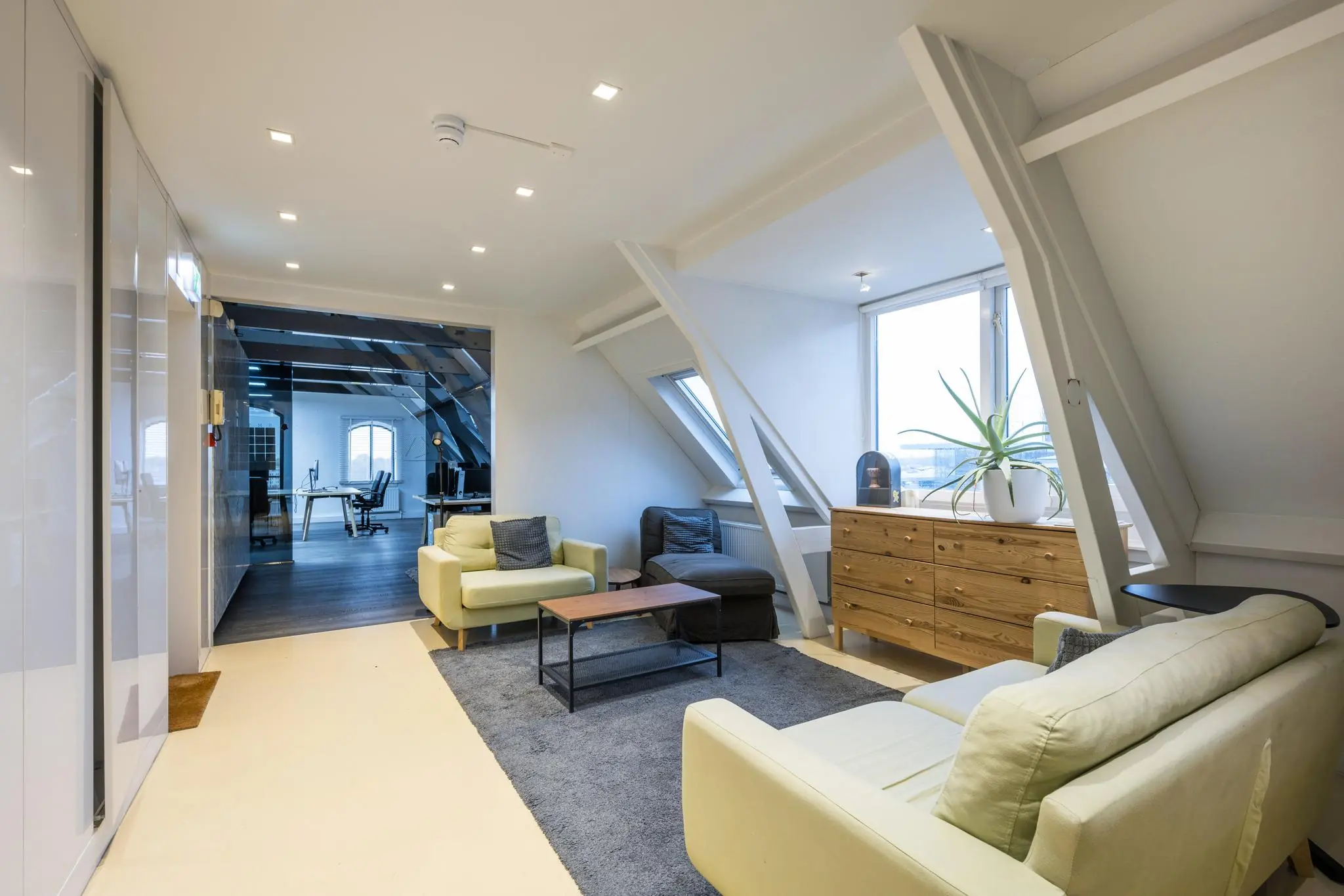 Moderne kantoorruimte aan de De Ruijterkade met een loungehoek, houten dressoir en uitzicht op de stad.