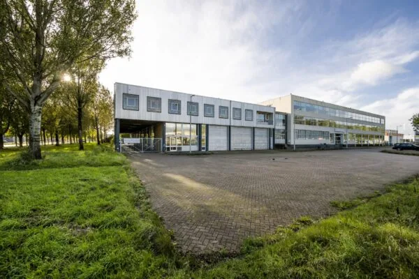 Bedrijfsgebouw aan de Van der Madeweg met parkeerterrein en omliggend groen.