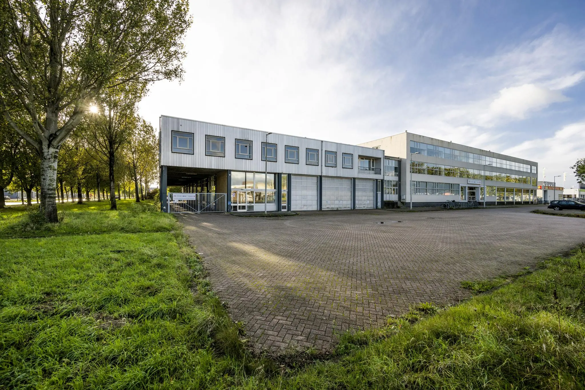 Bedrijfsgebouw aan de Van der Madeweg met parkeerterrein en omliggend groen.