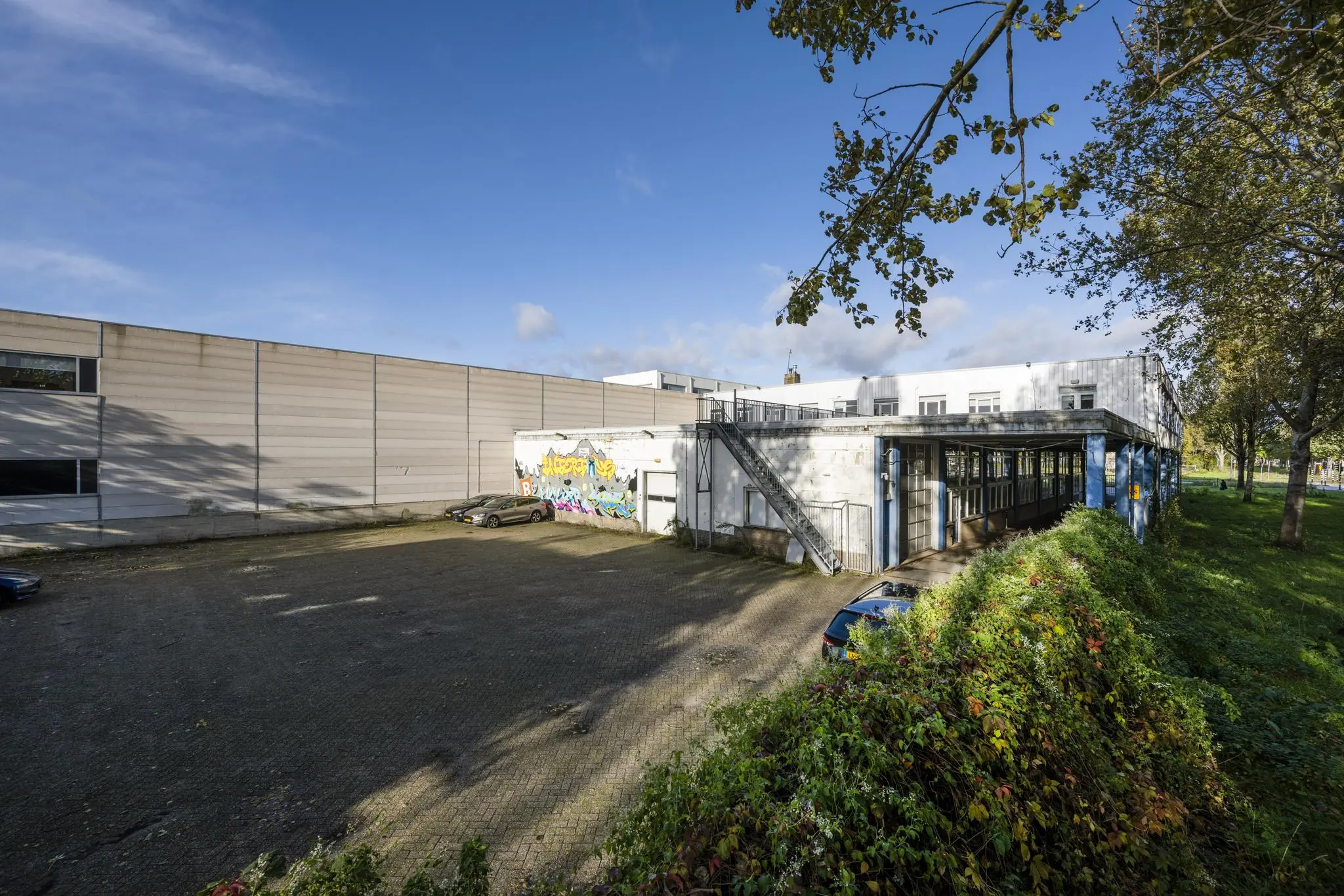 Bedrijfsgebouw aan de Van der Madeweg met graffiti op de gevel en een parkeerterrein op de voorgrond.