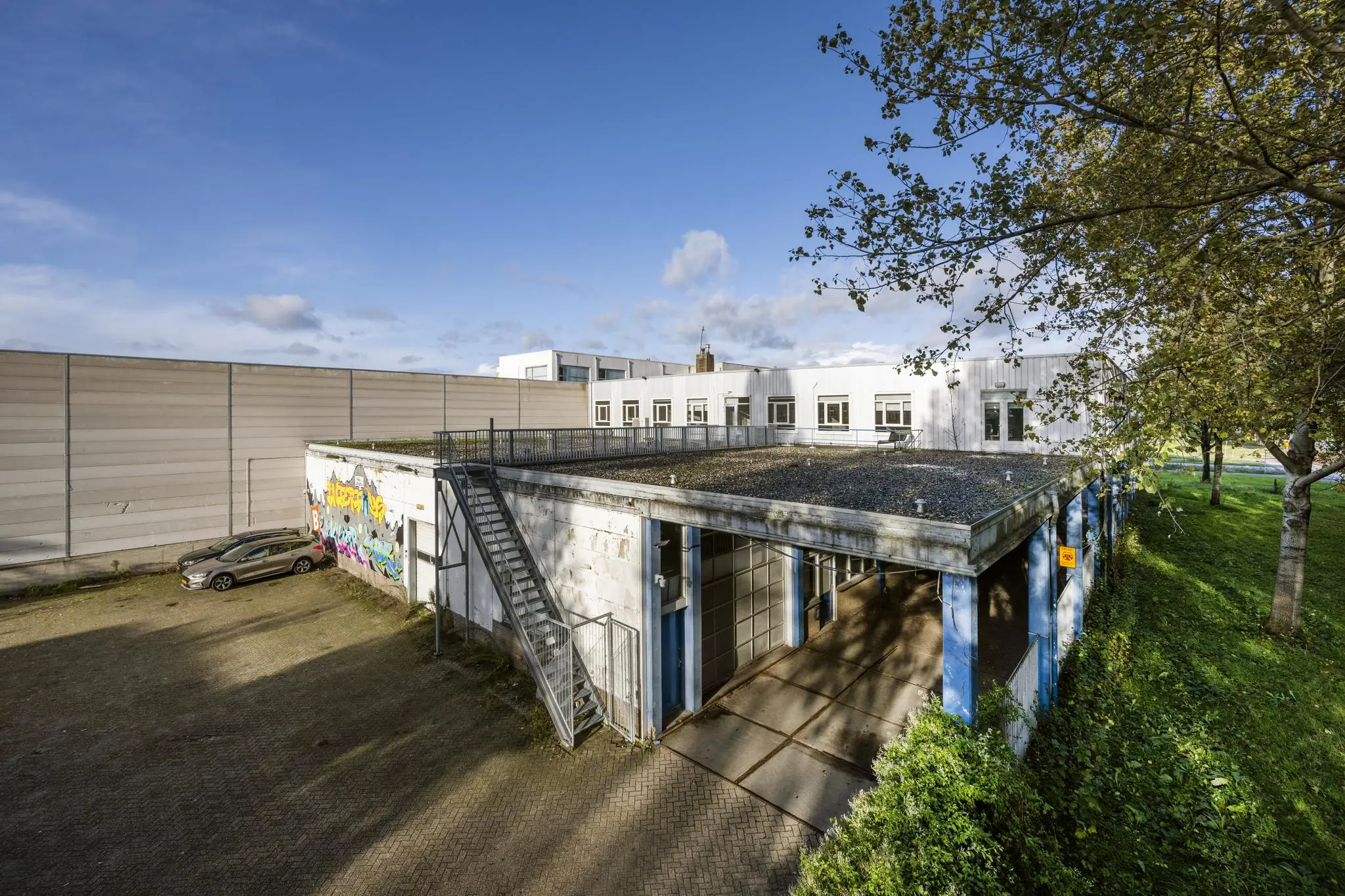 Bedrijventerrein aan de Van der Madeweg met wit gebouw, graffiti op de muur en geparkeerde auto.