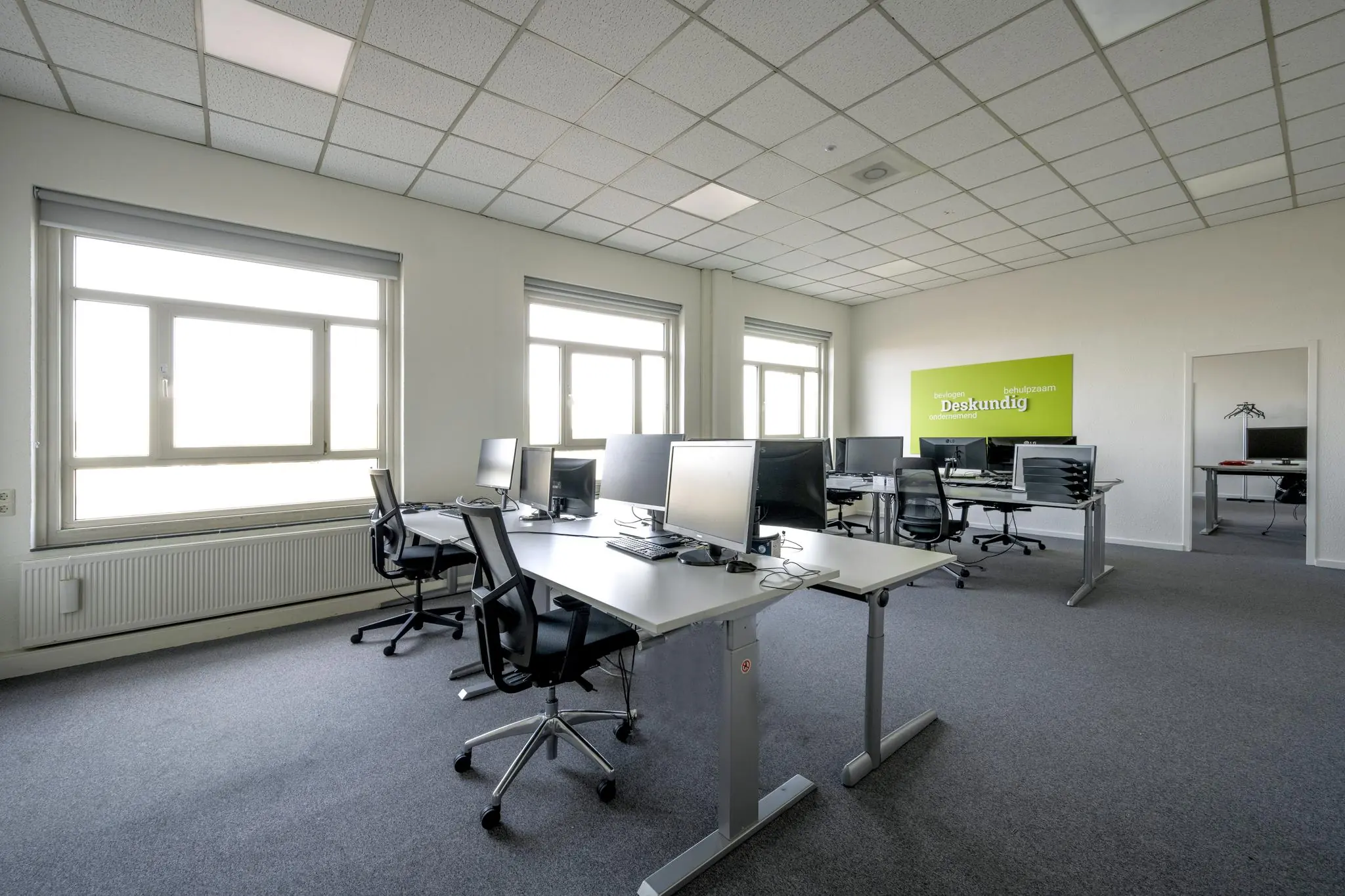 Modern kantoorinterieur aan de Van der Madeweg met meerdere werkplekken, bureaustoelen en computerschermen.