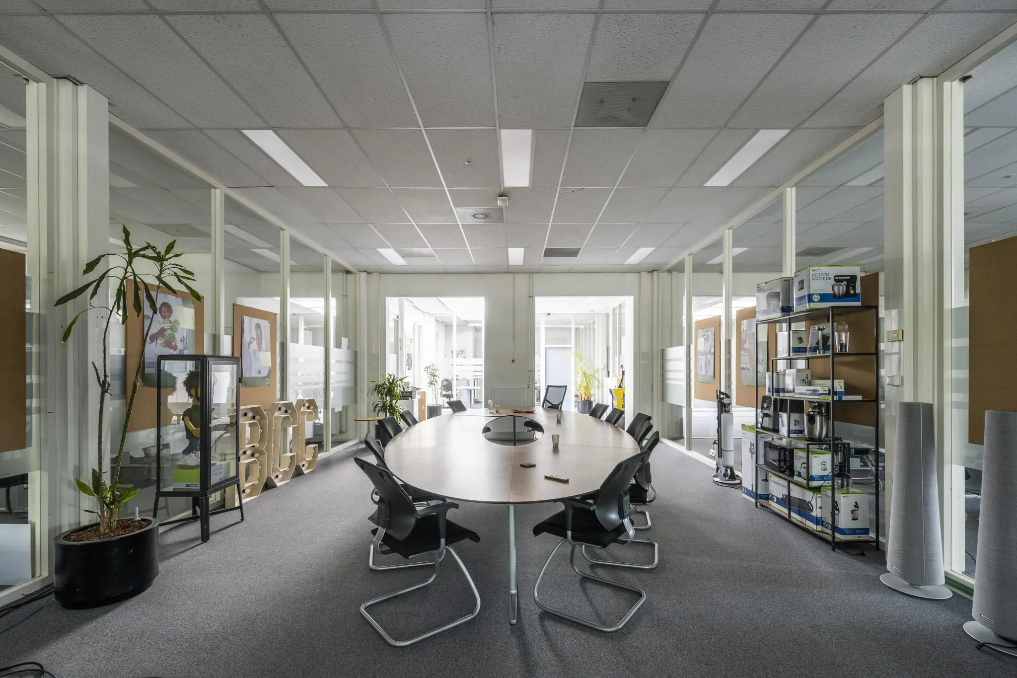 Vergaderruimte op kantoor aan de Van der Madeweg met een ovale tafel, stoelen en presentatierek met elektronica.