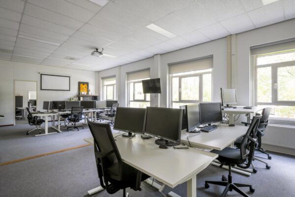 Ruime, moderne kantoortuin aan de Van der Madeweg met meerdere werkplekken, bureaustoelen en computers.
