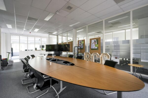 Moderne vergaderruimte aan de Van der Madeweg met ovale tafel, stoelen en presentatieschermen.