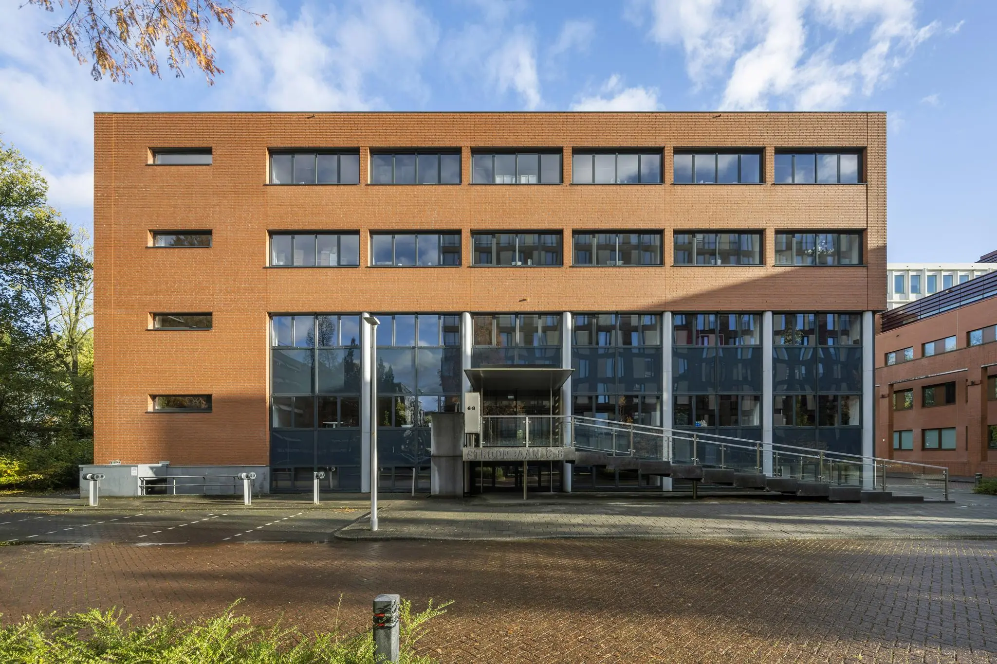 Vooraanzicht van het moderne kantoorgebouw Stroombaan 4-6 met een bakstenen gevel en glazen entree.