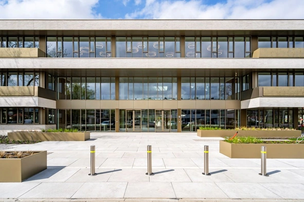 Moderne voorgevel van het Walborg-gebouw met grote glazen ramen en een strak aangelegd plein.