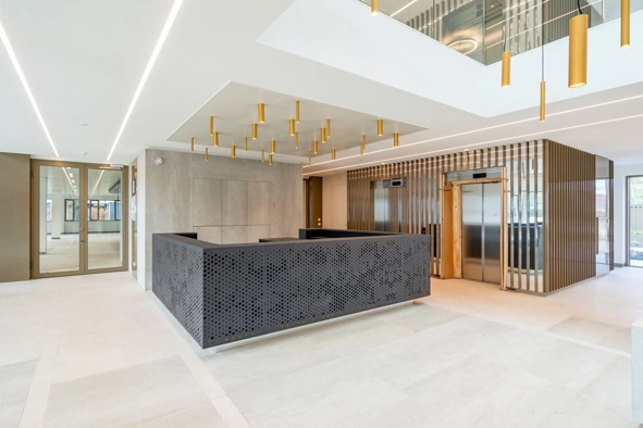 Moderne en stijlvolle lobby van het Walborg-gebouw met twee liften, een zwarte balie en goudkleurige accenten.