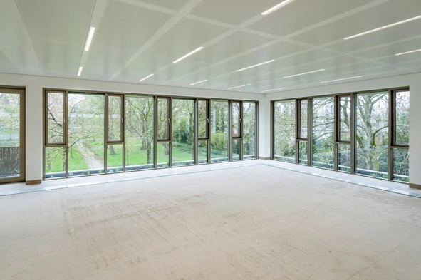 Lichte, lege kantoorruimte met grote ramen en uitzicht op een groene tuin in gebouw Walborg.