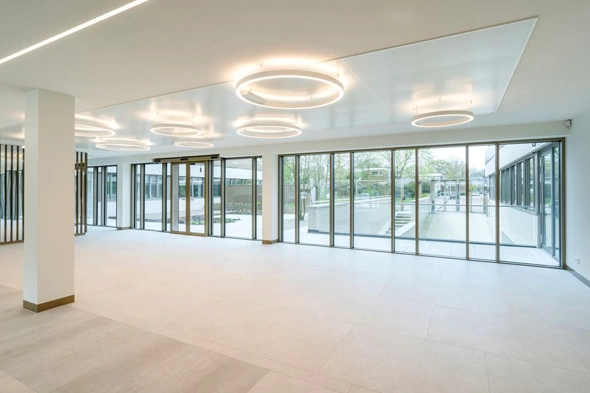 Moderne, lichte entreehal van een kantoorgebouw met grote ramen en ronde plafondverlichting aan Walborg.