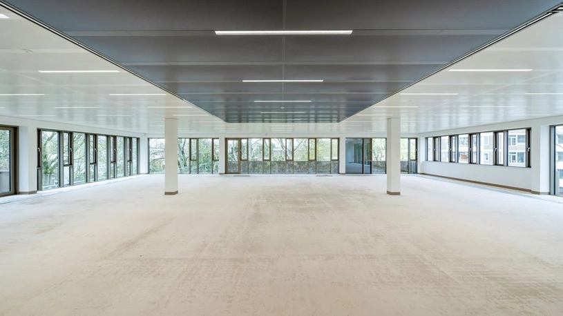 Lichte, lege kantoorruimte met grote ramen en uitzicht op bomen en omliggende gebouwen in gebouw Walborg.