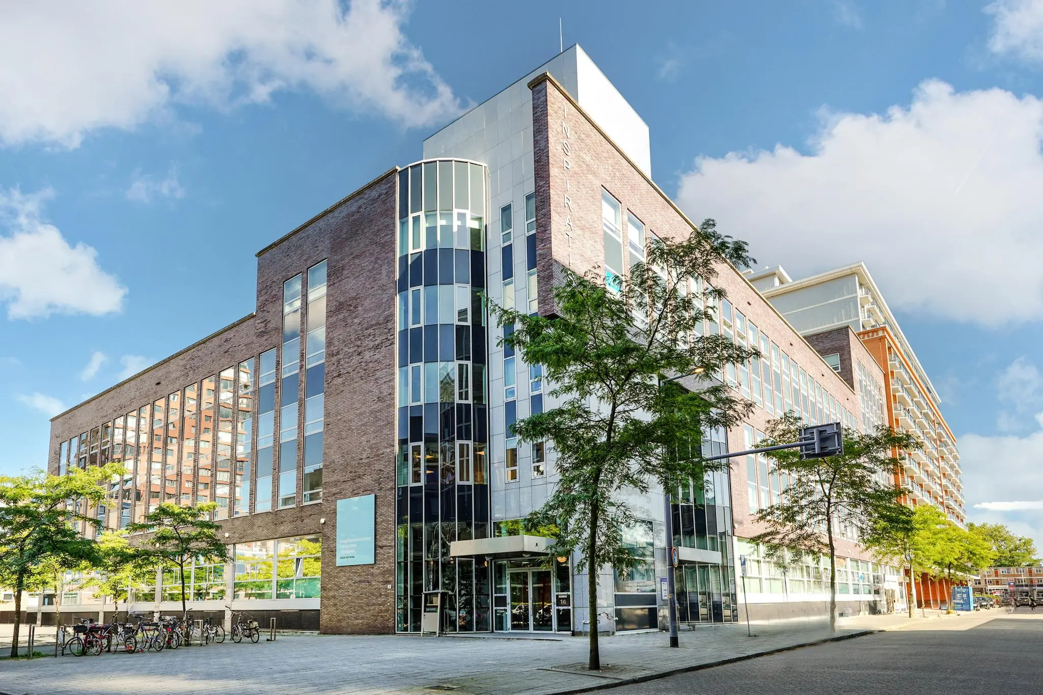Modern kantoorgebouw aan de Dynamostraat met grote glaspartijen en bomen langs de stoep.