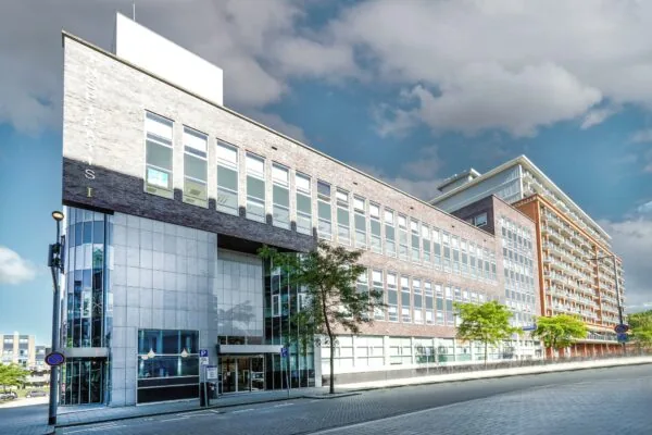 Modern kantoorgebouw aan de Dynamostraat met grote ramen en betegelde gevel, bij helder weer gefotografeerd.