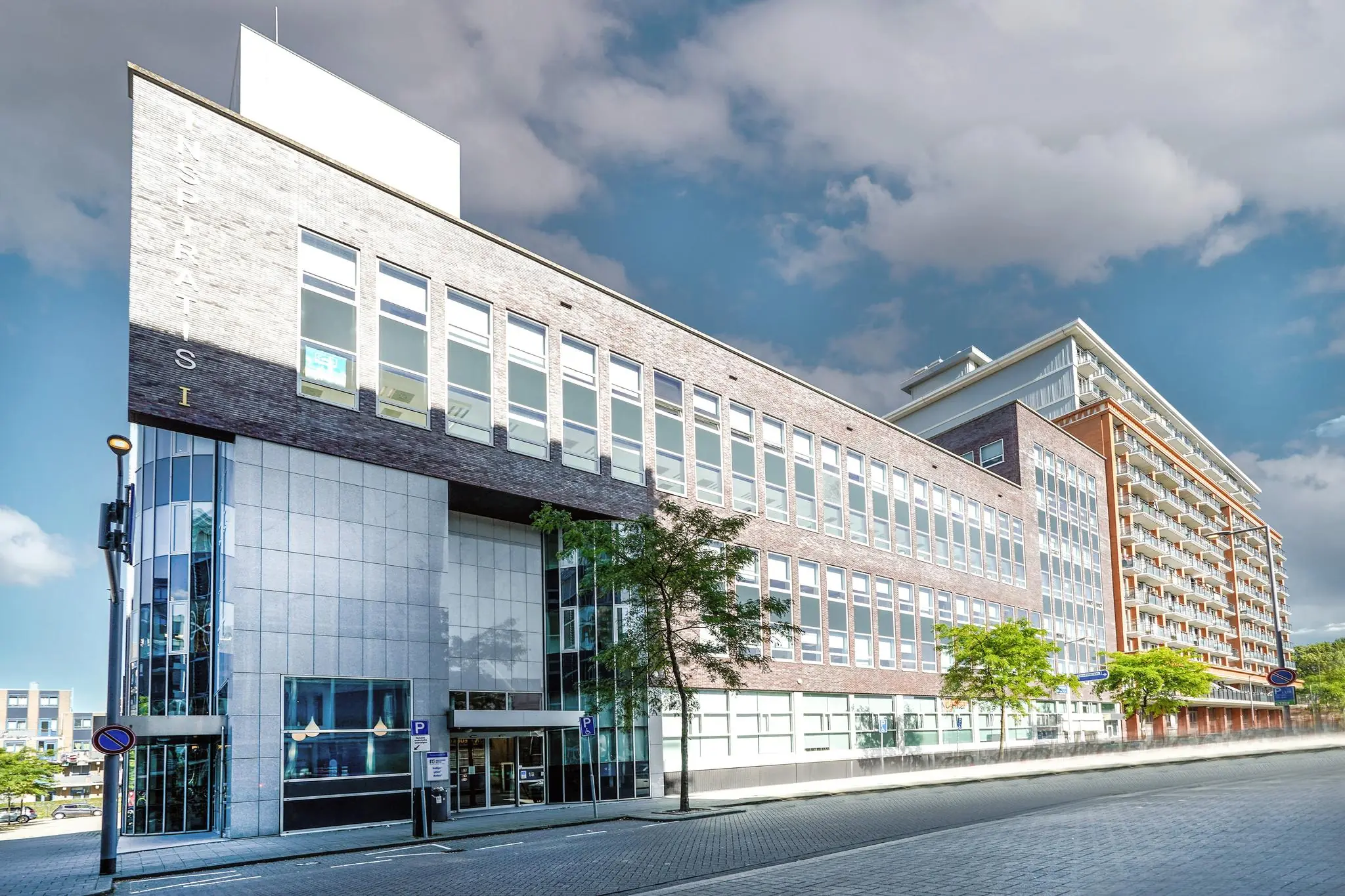 Modern kantoorgebouw aan de Dynamostraat met grote ramen en betegelde gevel, bij helder weer gefotografeerd.