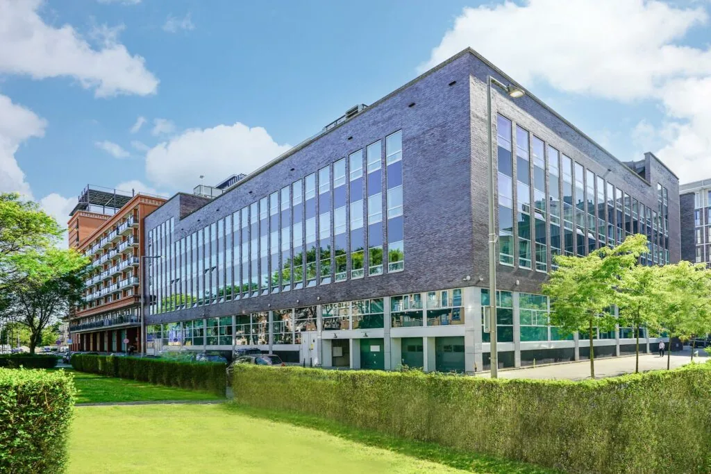 Modern kantoorgebouw aan de Dynamostraat met grote glaspartijen en omliggend groen.