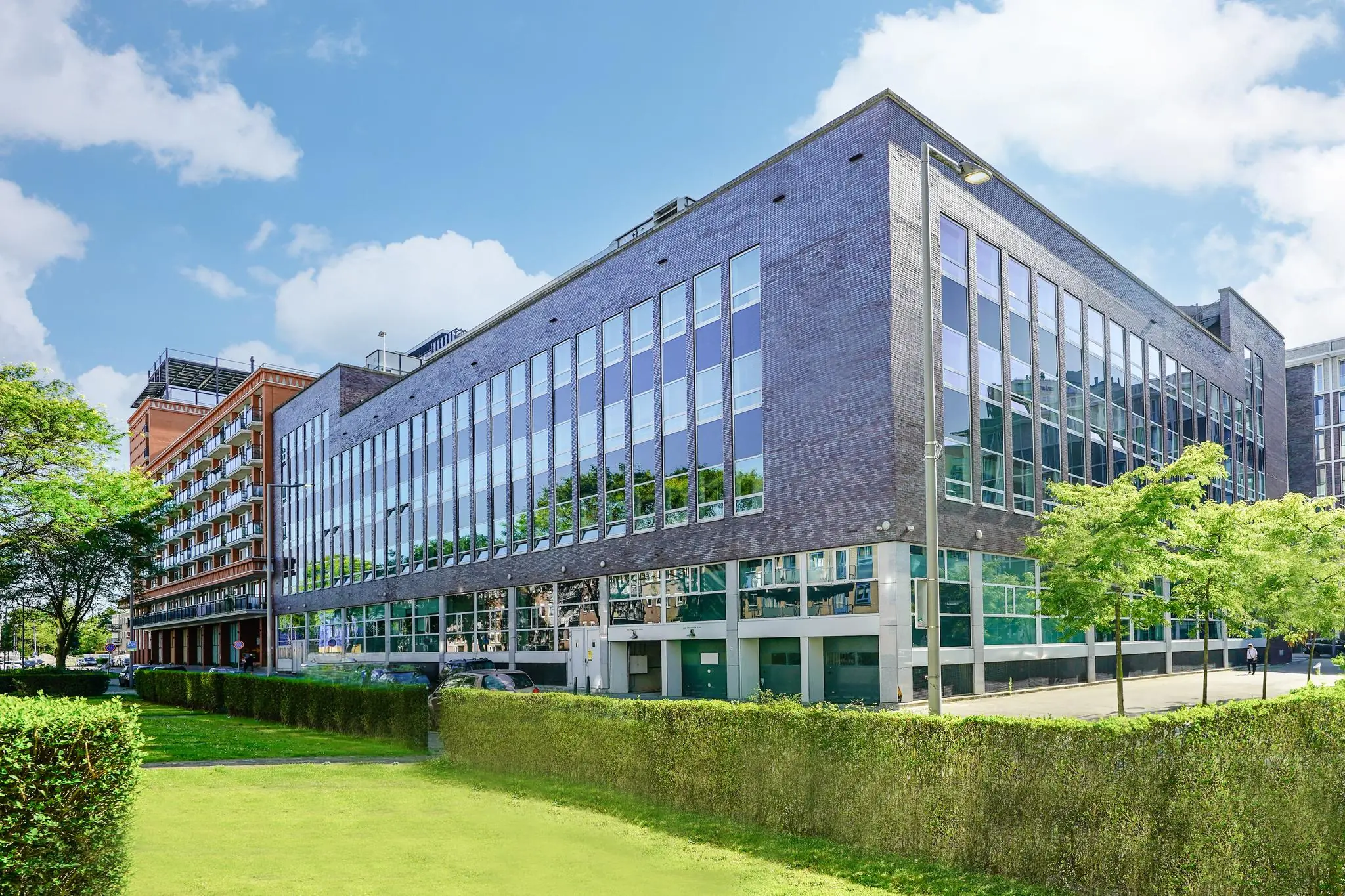 Modern kantoorgebouw aan de Dynamostraat met grote glaspartijen en omliggend groen.