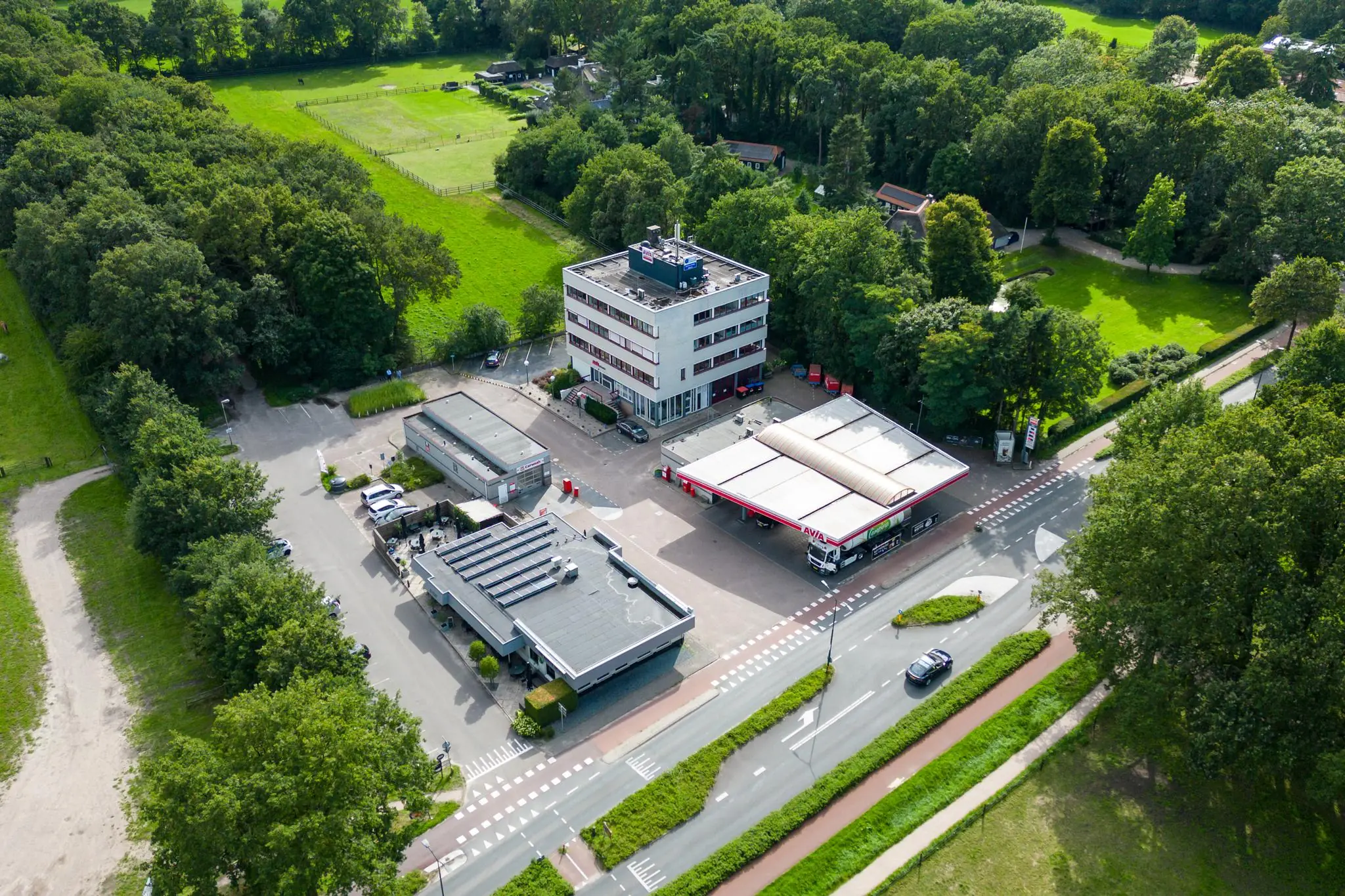 Luchtfoto van een AVIA tankstation met naastgelegen kantoorgebouw aan de Birkstraat, omringd door groen.
