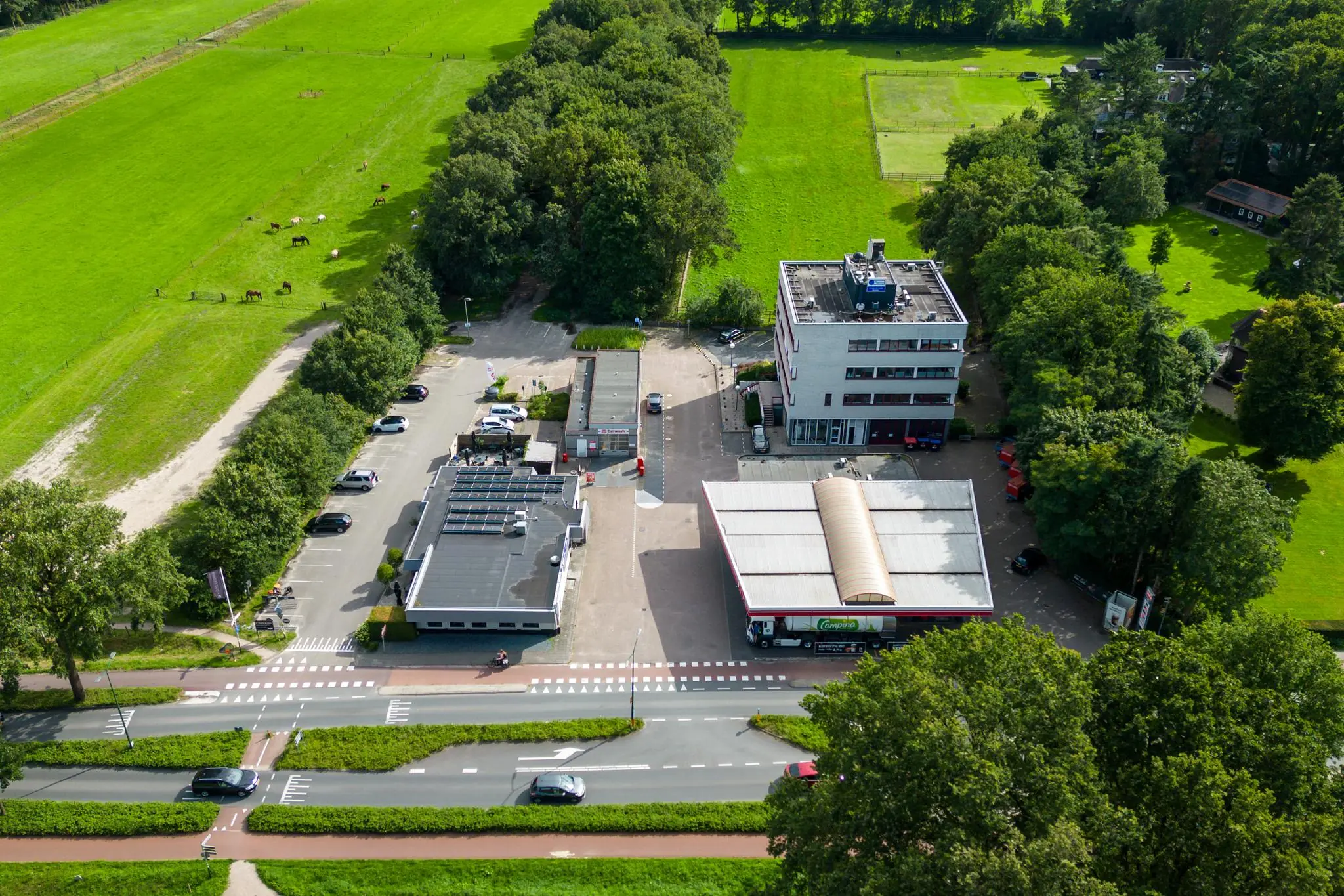 Luchtfoto van een bedrijventerrein aan de Birkstraat, omringd door groene weilanden en bomen.